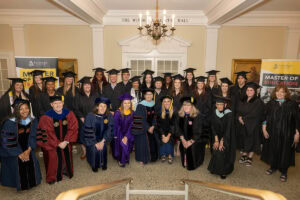 A group of Master of Arts in Teaching and Master of Education graduates pose with faculty. 