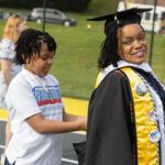 Sonia Langhorne '25 smiles as her son, acting as her squire, helps her with her hood during Commencement Sonia Langhorne '25 smiles as her son, acting as her squire, helps her with her hood during Commencement