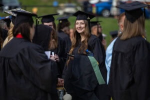 Students, in their caps and gowns, stand together after Commencement