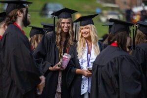 Two students in caps and gowns smile for a photo 