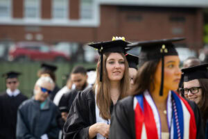 Students sit in the crowd in their caps and gowns during Commencement 