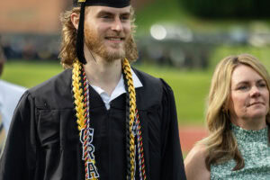 A student wearing a cap and gown smiles during the 2025 Commencement ceremony 