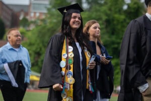 A student wearing a cap and gown smiles during the 2025 Commencement ceremony 