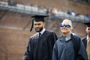 A student wearing a cap and gown smiles during the 2025 Commencement ceremony 