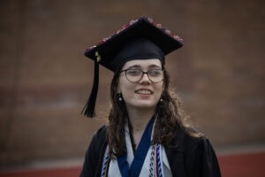 A student wearing a cap and gown smiles during the 2025 Commencement ceremony 