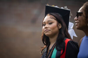 A student wearing a cap and gown smiles during the 2025 Commencement ceremony 