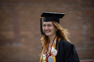 A student wearing a cap and gown smiles during the 2025 Commencement ceremony 