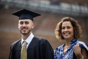 A student wearing a cap and gown smiles during the 2025 Commencement ceremony 