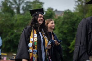 A student wearing a cap and gown smiles during the 2025 Commencement ceremony 