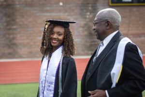 A student wearing a cap and gown smiles during the 2025 Commencement ceremony 