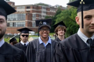 A student wearing a cap and gown smiles during the 2025 Commencement ceremony 