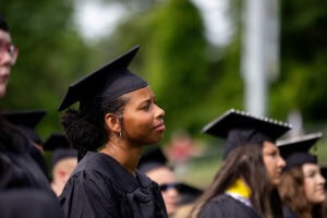 Students sit in the crowd in their caps and gowns during Commencement 