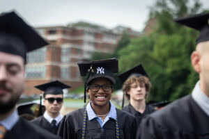 Students sit in the crowd in their caps and gowns during Commencement 