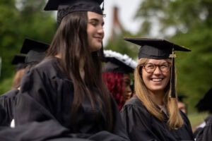 Students sit in the crowd in their caps and gowns during Commencement 