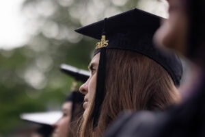 Students sit in the crowd in their caps and gowns during Commencement 