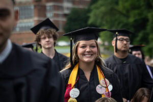 A student wearing a cap and gown smiles during the 2025 Commencement ceremony 