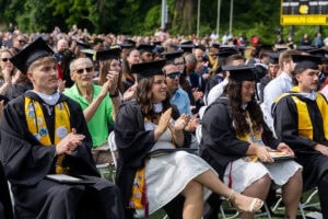 Students sit in the crowd in their caps and gowns during Commencement 