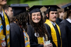 A student wearing a cap and gown smiles during the 2025 Commencement ceremony 