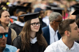 Students, in their caps and gowns, smile in the crowd during their Commencement ceremony