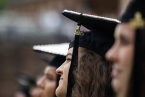 Students, in their caps and gowns, smile in the crowd during their Commencement ceremony