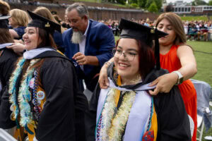 Students smile as their squires "hood" them during Commencement 