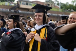 Students, in their caps and gowns, smile in the crowd during their Commencement ceremony