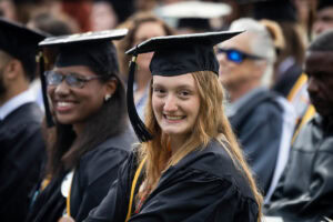 Students, in their caps and gowns, smile in the crowd during their Commencement ceremony