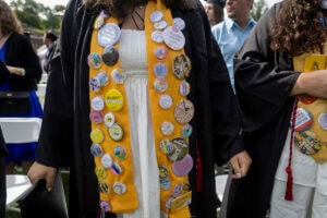A close-up of a yellow stole covered in buttons during Commencement 