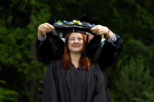 A graduate student receives their hood onstage during Commencement