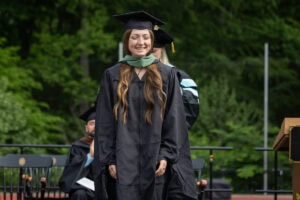A graduate student receives their hood onstage during Commencement