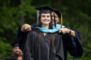 A graduate student receives their hood onstage during Commencement