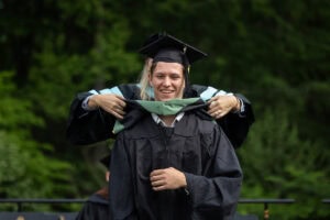 A graduate student receives their hood onstage during Commencement