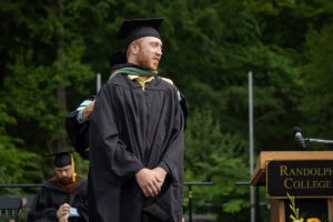 A student stands onstage after receiving his hood during Commencement 