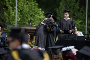 A student hugs President Sue Ott Rowlands while receiving their diploma onstage