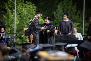 A student shakes President Sue Ott Rowlands' hand while receiving his diploma 