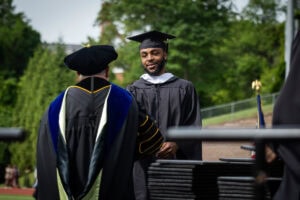 A student in his cap and gown receives his diploma onstage during Commencement
