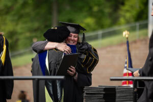 A graduate hugs President Sue Ott Rowlands as she receives her diploma 