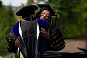 A graduate hugs President Sue Ott Rowlands as she receives her diploma 