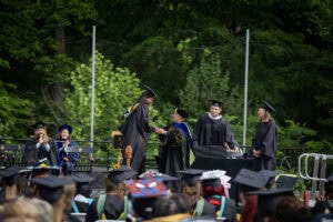 A graduate in a cap and gown receives her diploma from President Sue Ott Rowlands