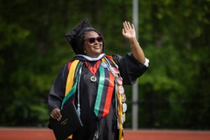 A graduate smiles and waves to the crowd during Commencement 