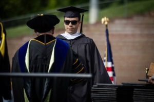 A student in sunglasses receives his diploma from President Sue Ott Rowlands