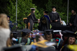 A graduate in a cap and gown receives her diploma from President Sue Ott Rowlands