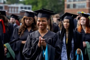 Students in caps and gowns smile in the crowd during the Commencement ceremony
