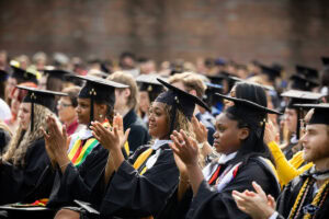 Students sit in the front row during Commencement, clapping 