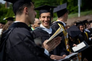 Graduates in the Commencement crowd smile at each other 