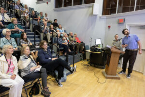 A man speaking to a crowd in a lecture hall.