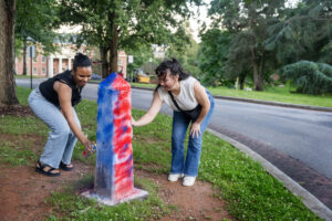 Two alums spray paint the Even Post during Reunion