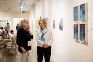 Ann Holsberry speaks to a fellow alum about her Maier exhibit during Reunion