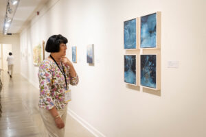 An alum looks at art hanging in the Maier during Reunion