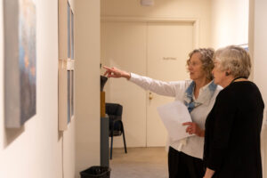 Ann Holsberry speaks to a fellow alum about her Maier exhibit during Reunion